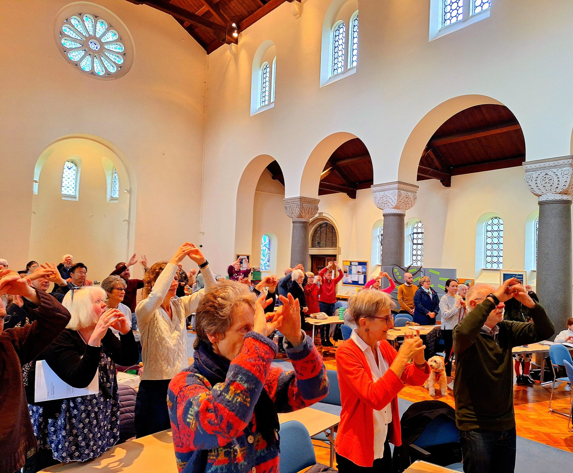 A congregation of people in brightly coloured clothing stand together doing sign language