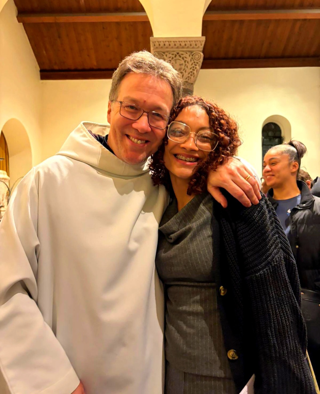 The Parish Priest stands smiling beside a young parishioner on the day of her confirmation